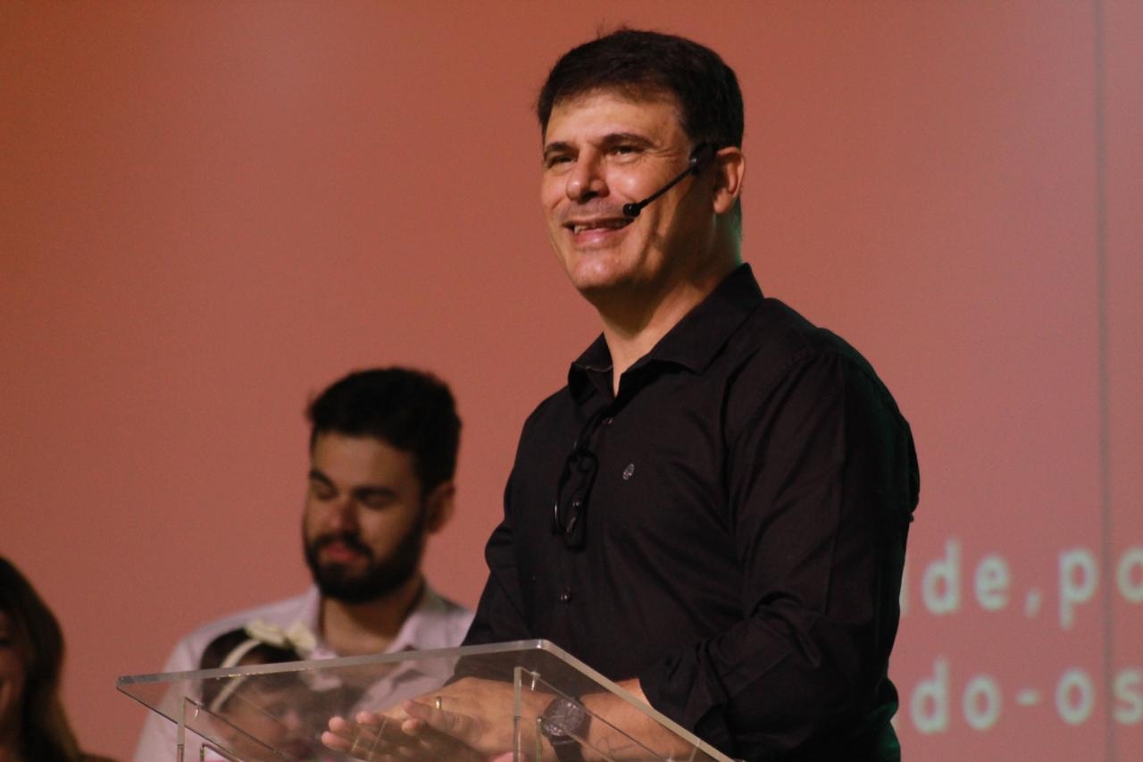 Imagem do pastor Júnior sorrindo durante uma pregação na igreja.